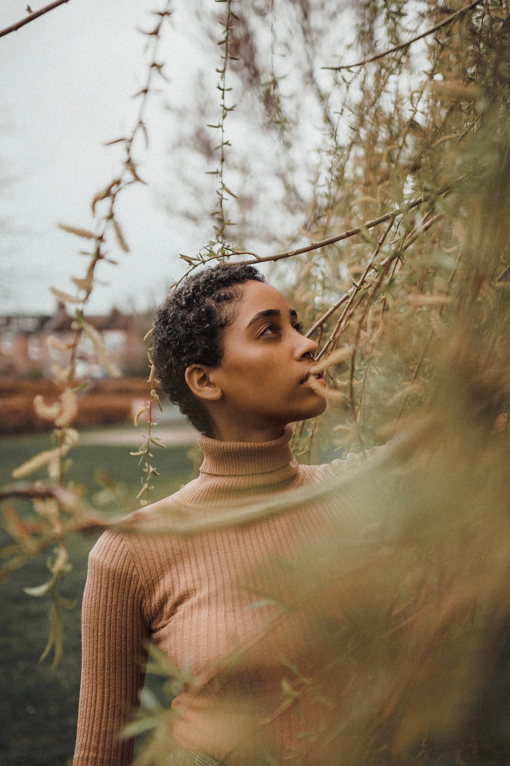 woman in beige sweater standing by brown foliage