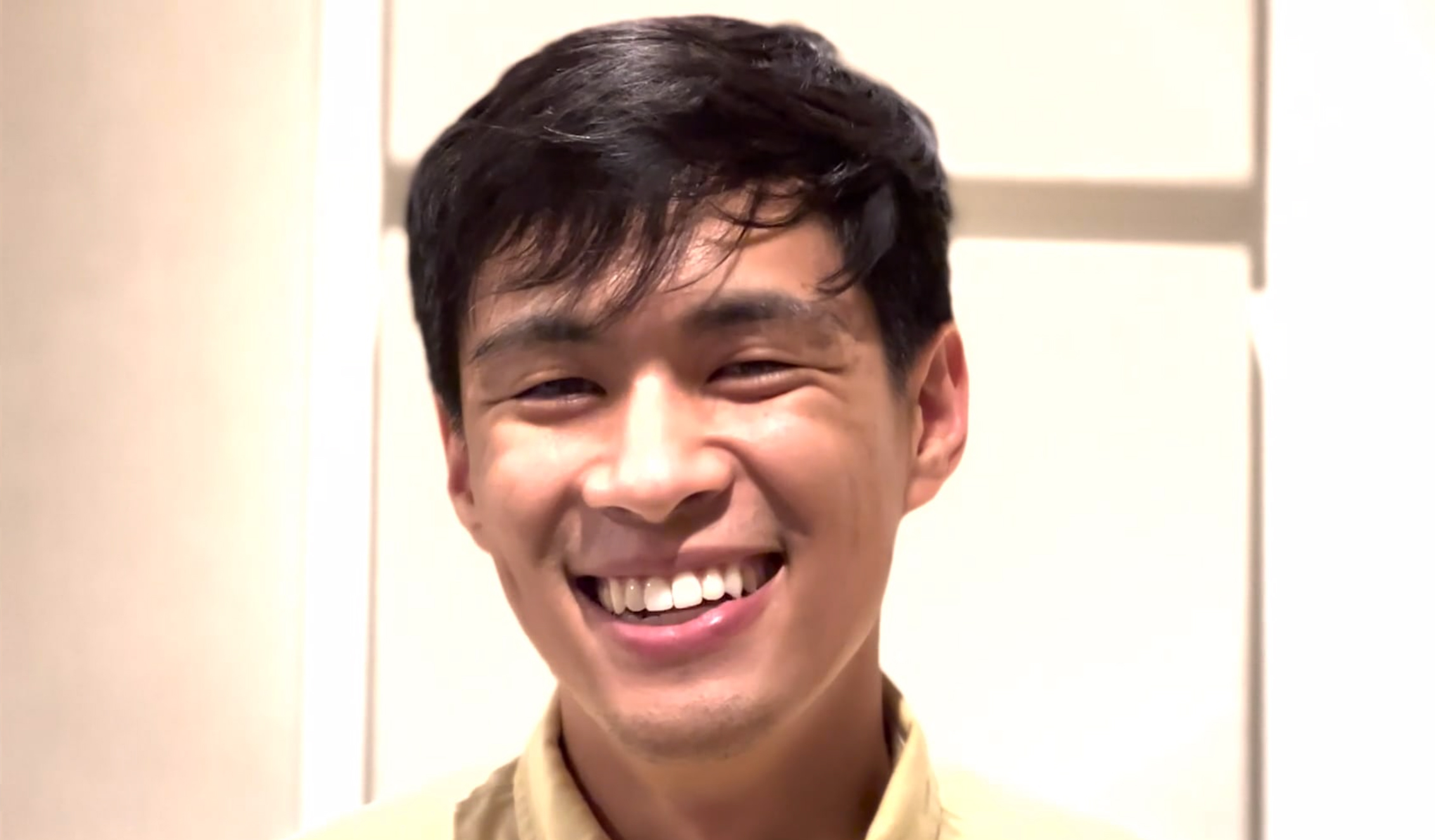 Closeup photo of a young man smiling against a white background