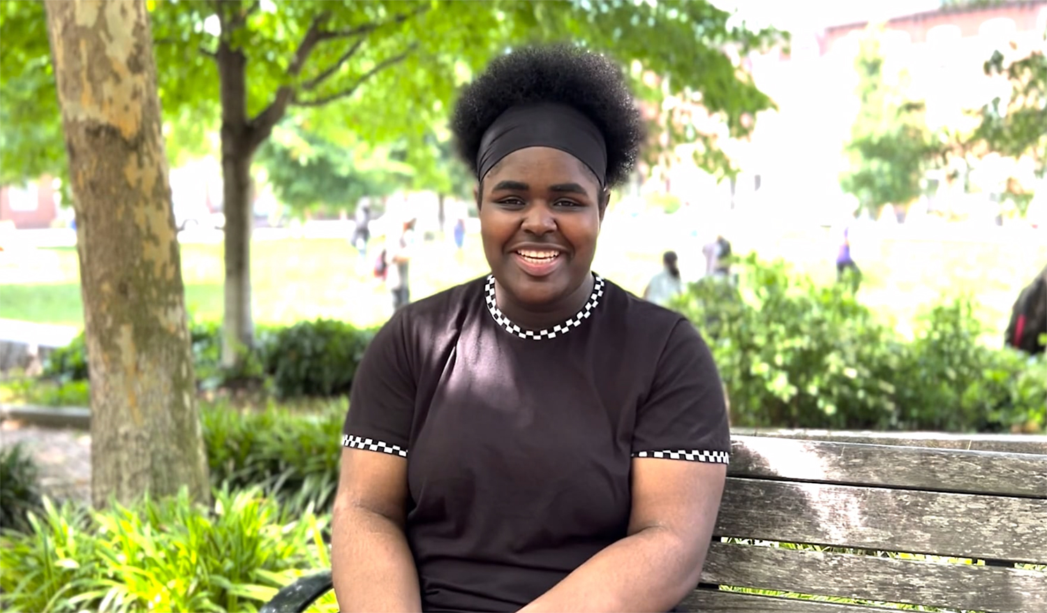 Young Black woman smiling while sitting on a park bench