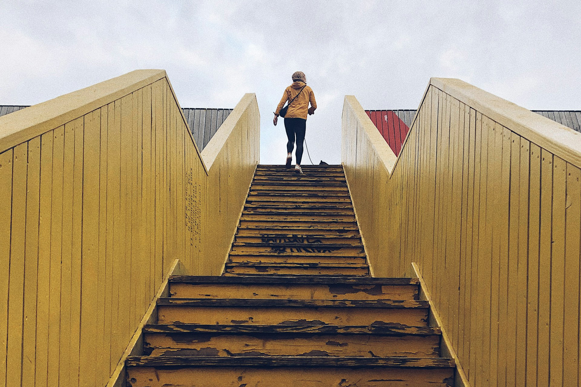 A woman walking up a long set of stairs toward the horizon