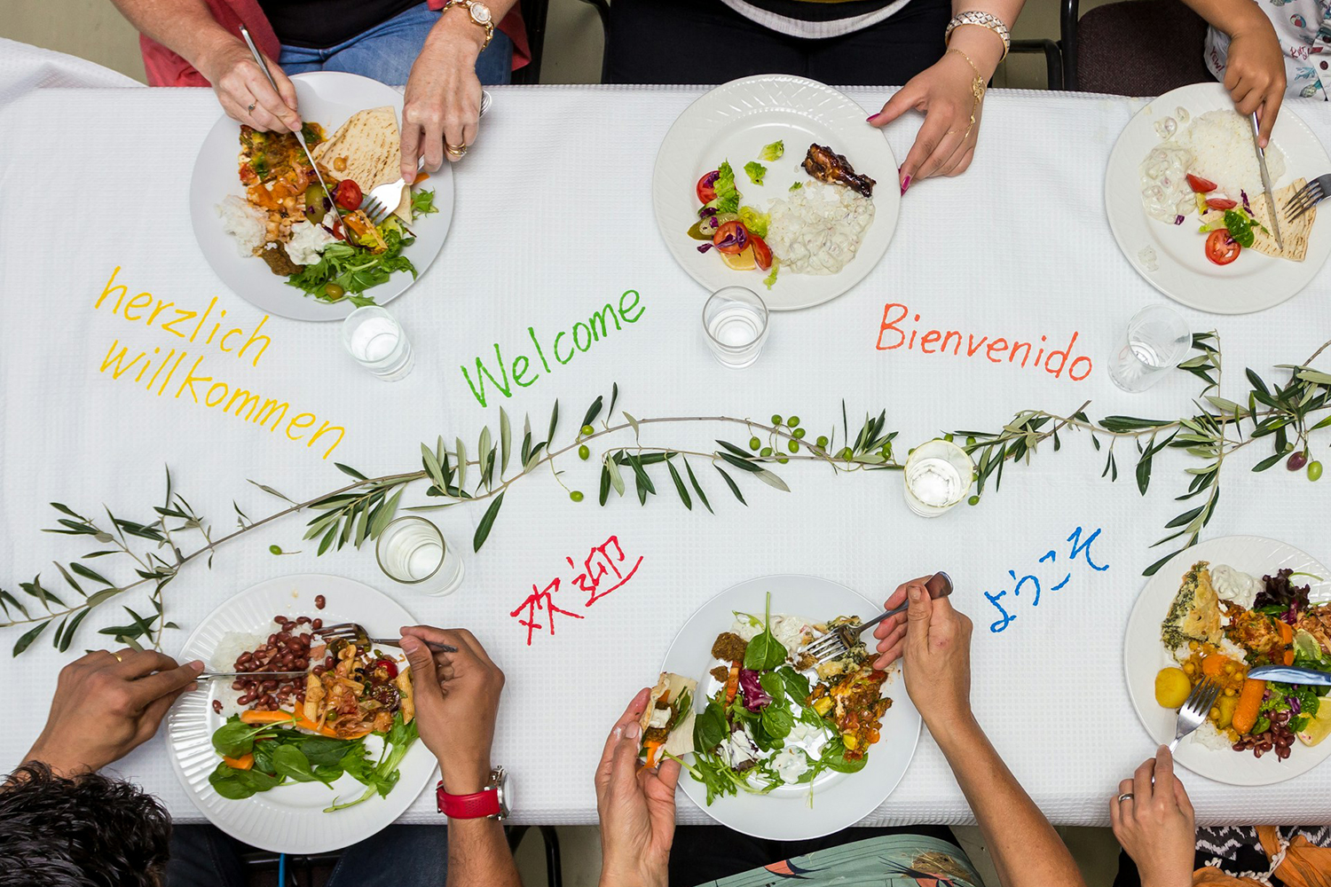 people sitting at dinner table with the word welcome written in different languages