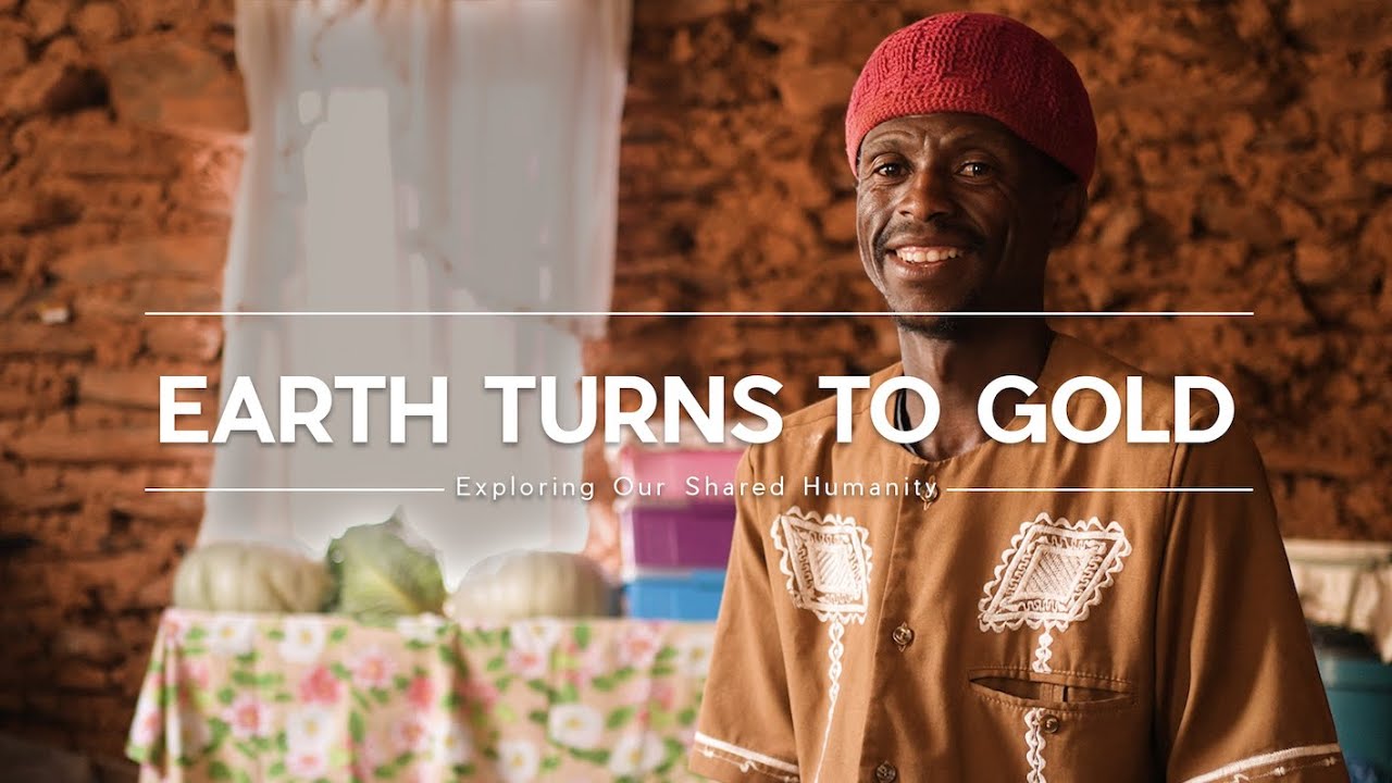 Man sitting in a room and smiling with text that reads "Earth Turns to Gold"