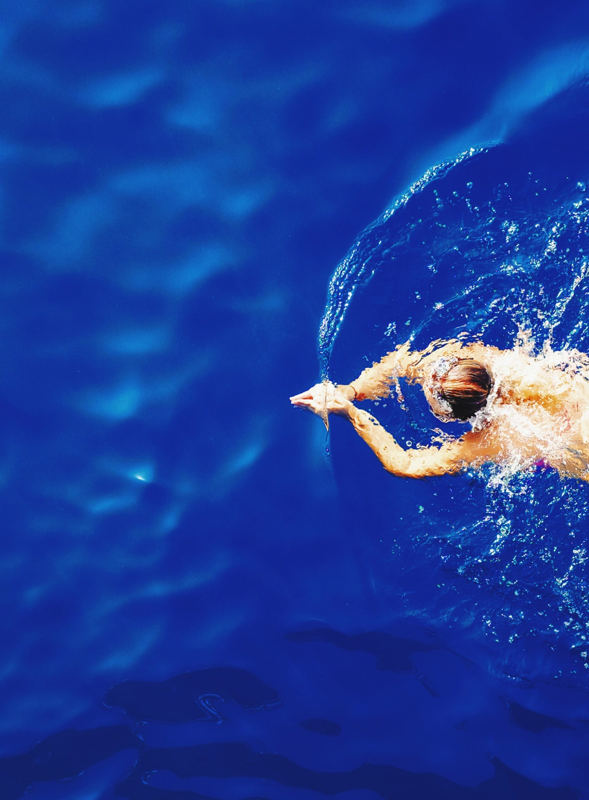 A person swimming through ripples in royal blue water.