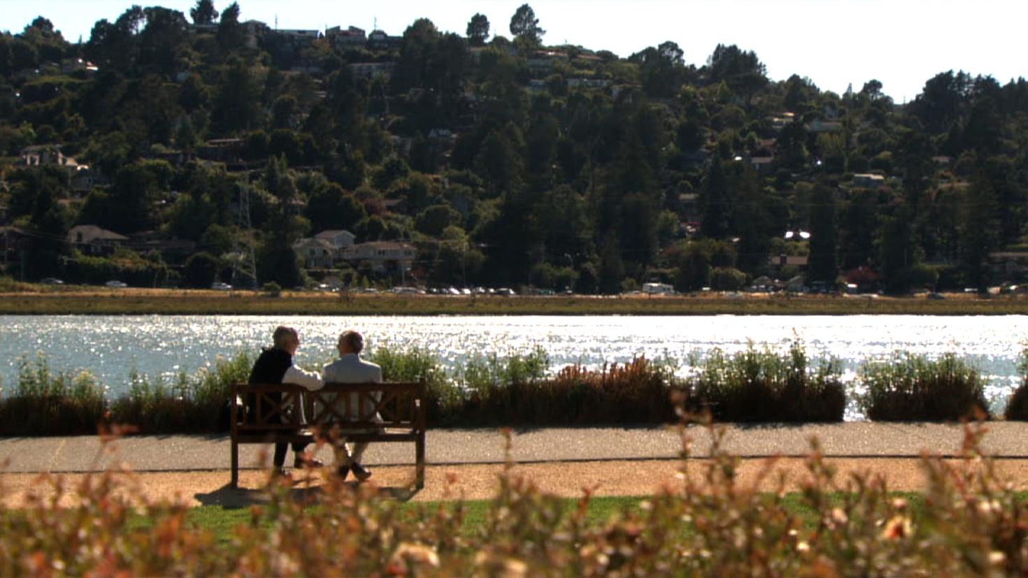 Br. David Steindl-Rast and Jack Kornfield sitting on a park bench facing a lake