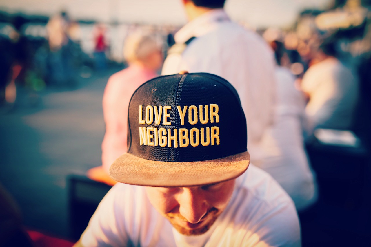 A man wearing a Love Your Neighbour baseball cap.