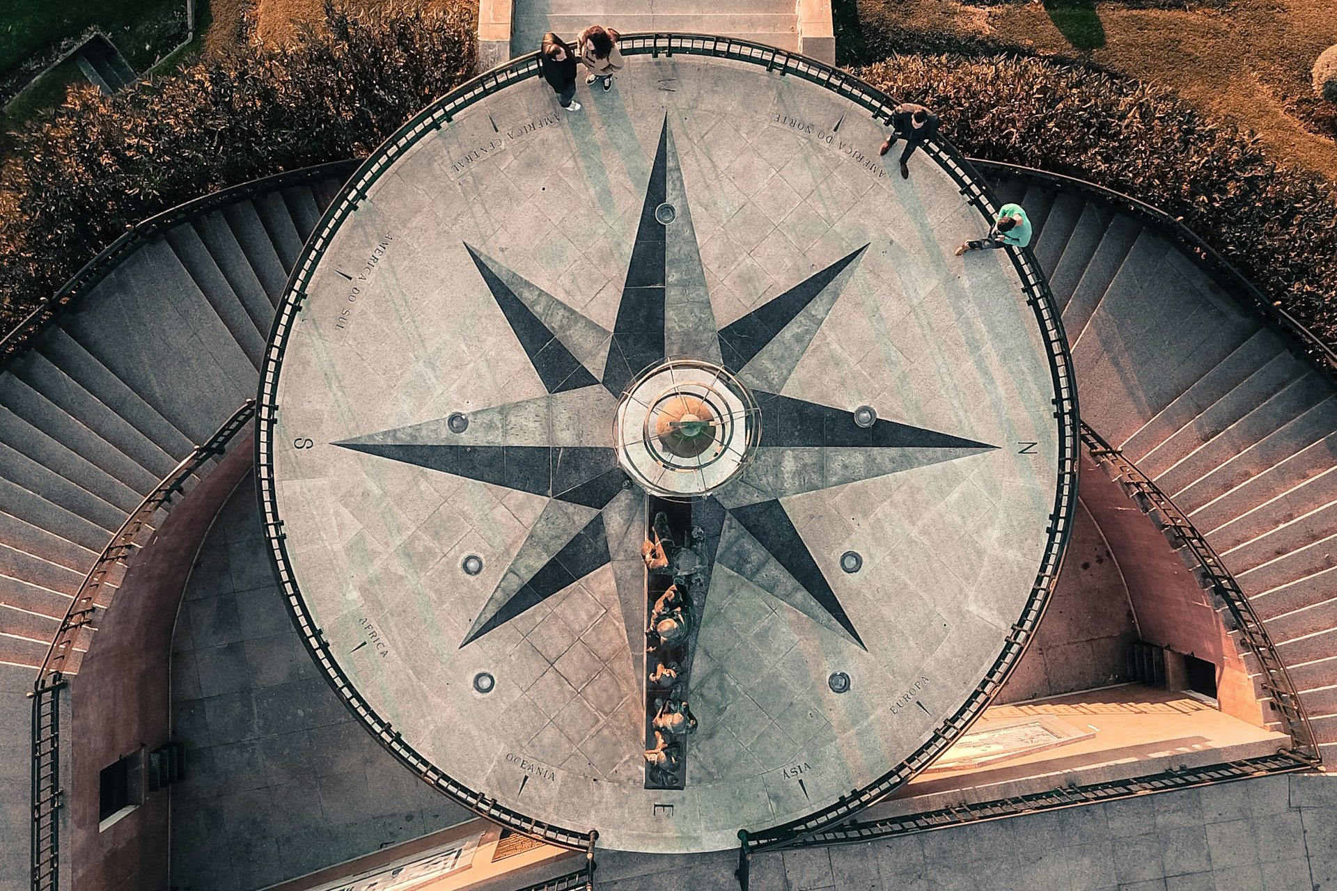 aerial view of a large compass on the ground with people around it