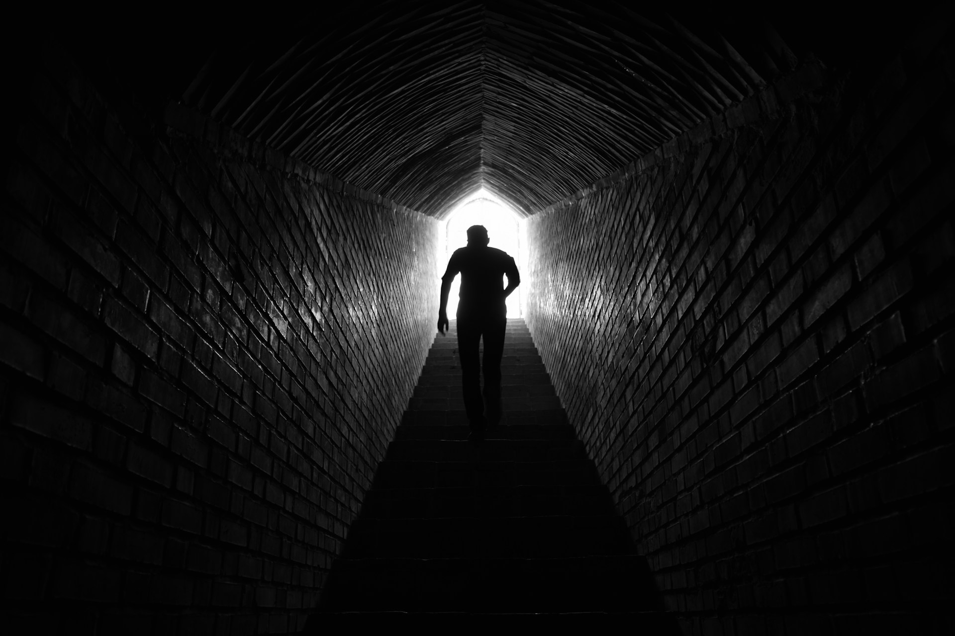 Man climbing stairs toward light
