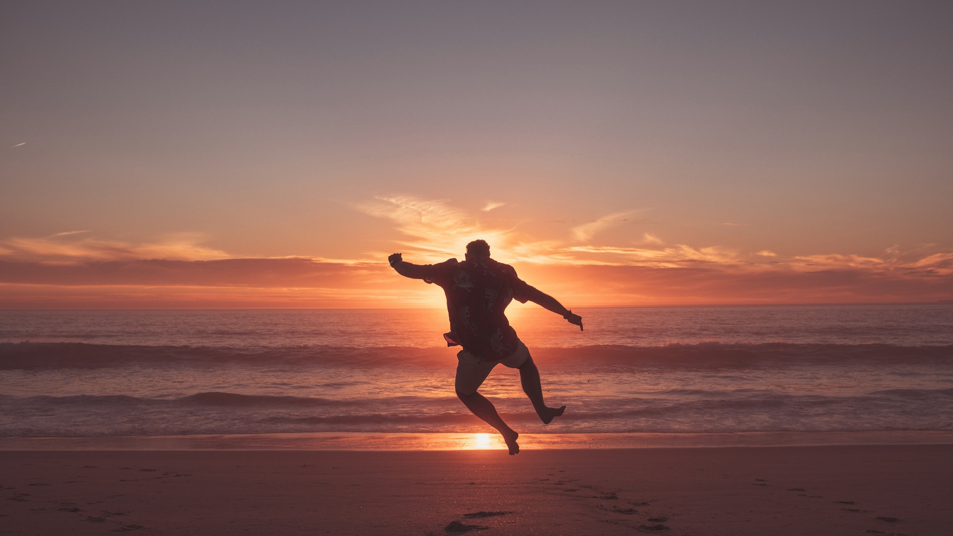 Man jumping on the beach at sunset