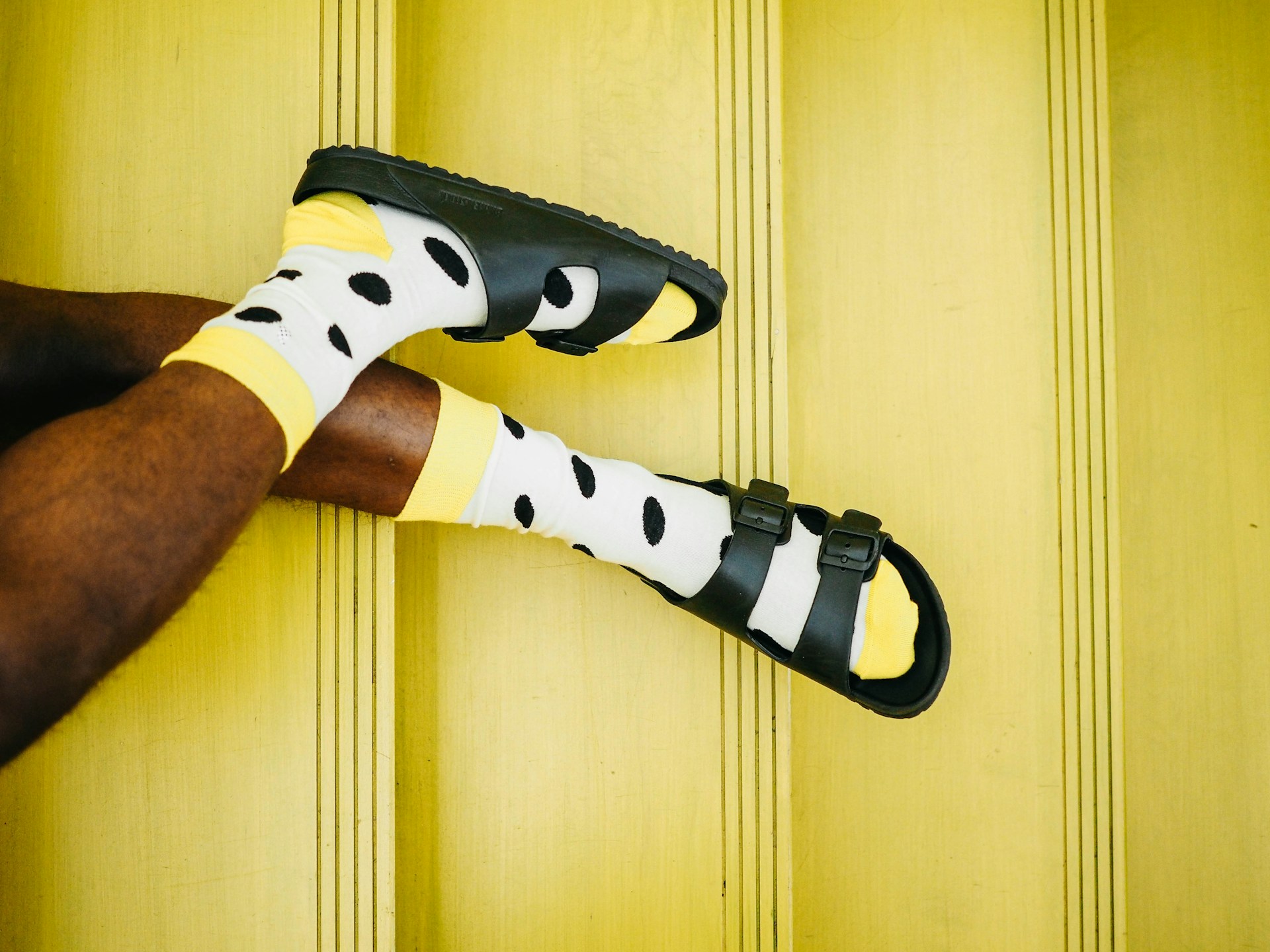 Man wearing bright polka dot socks with sandals against yellow steps