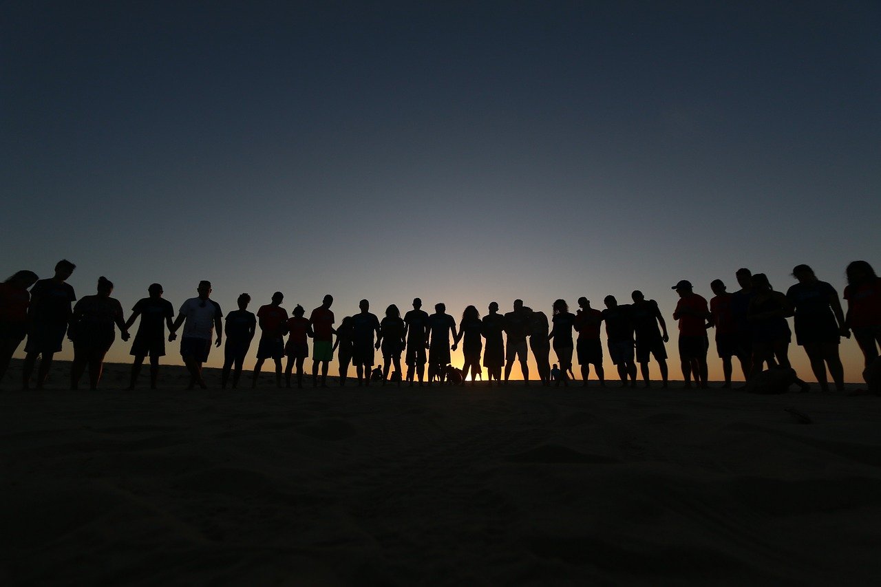 Silhouette of group of people holding hands.