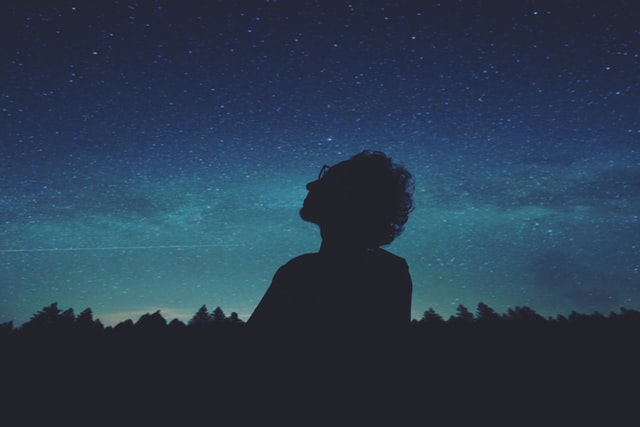 silhouette of person gazing up at night sky