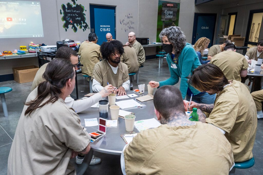 Artist and instructor Brooke Rothshank speaks to a table of incarcerated men during a five-session course on painting miniatures with an emphasis on gratitude