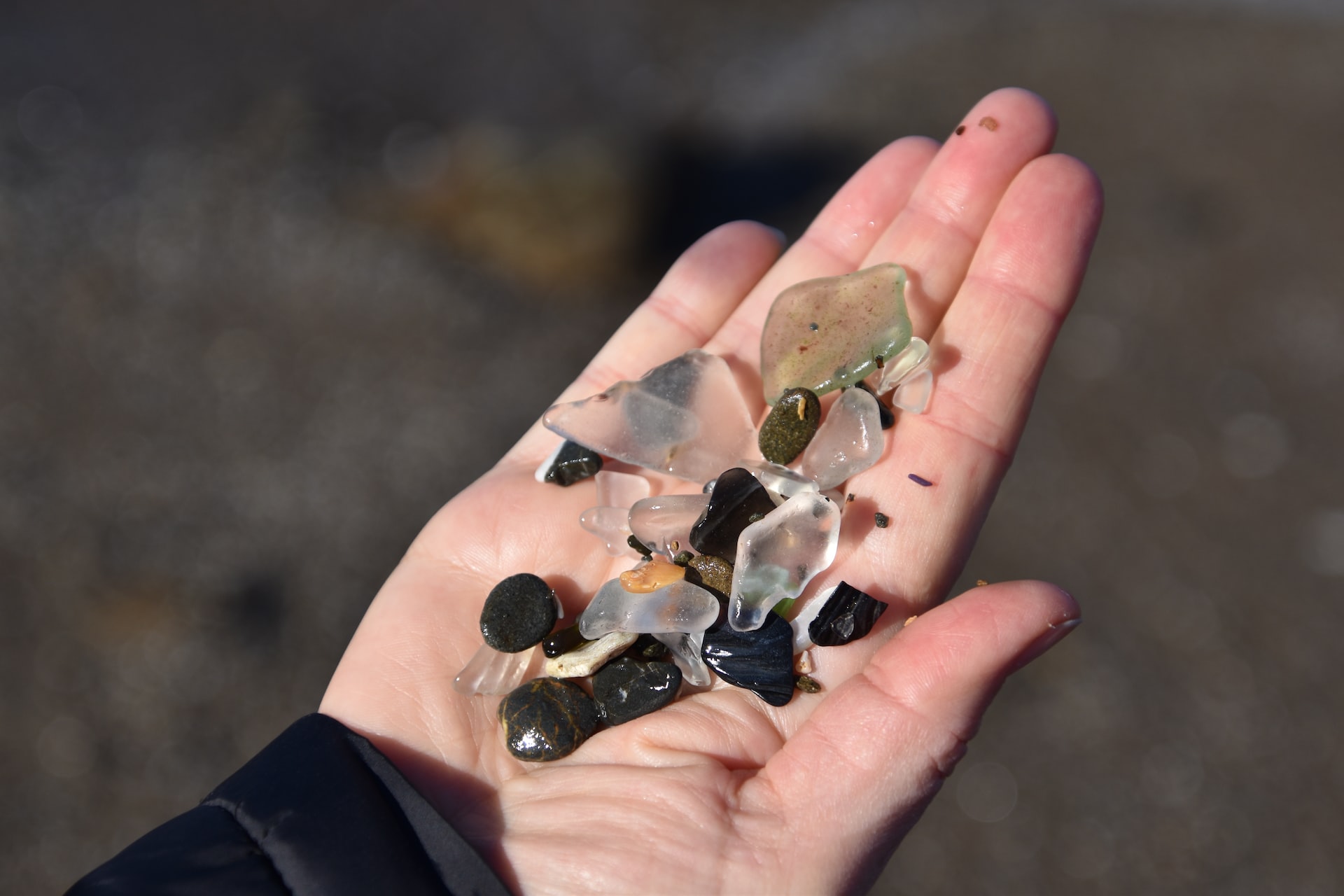 Open hand filled with bits of opaque sea glass and pebbles.