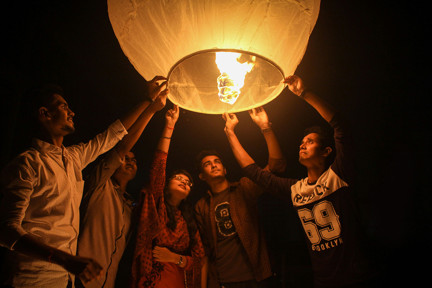 Group of young people holding onto a paper lantern