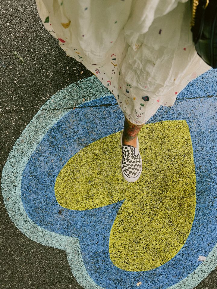 person walking over a yellow and blue heart on concrete ground