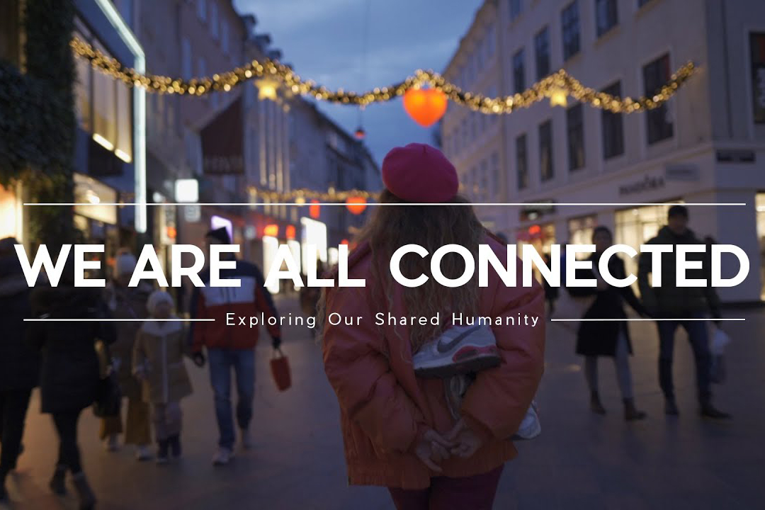 A woman faced away from the camera walking down a city street full of people with text that reads "We are all connected"