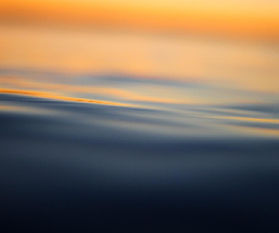 Calm water with a light orange reflection of the sky
