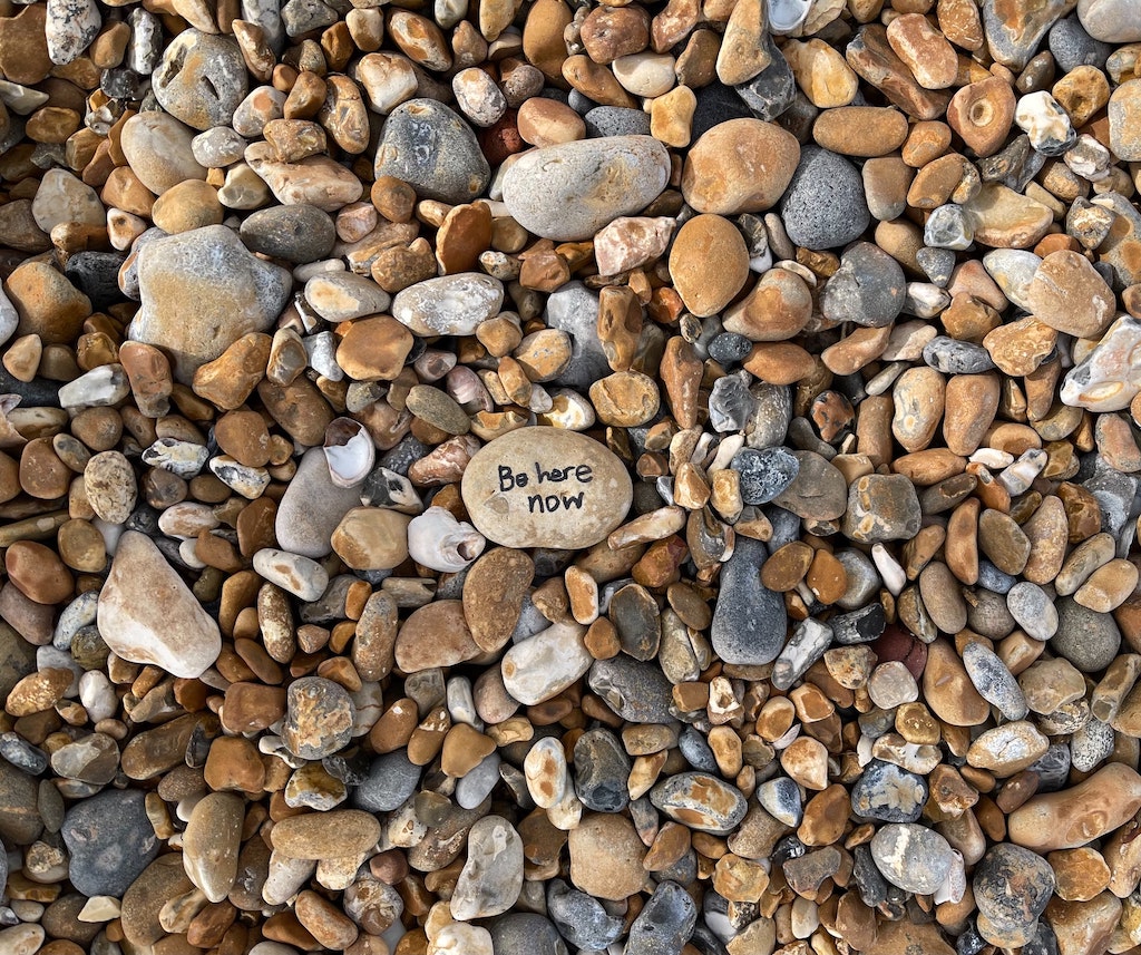 rocks with "be here now" written on the center-most rock