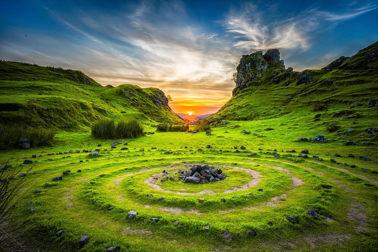 Green grass with a spiral labyrinth path leading to a formation of stones